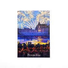 Carte postale puzzle reconstitué de la Cinéscénie : château éclairé sous un ciel embrasé de feux d'artifice, reflets sur l'eau et public