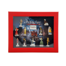 Vue de face du coffret rouge fermé Puy du Fou : fenêtre transparente avec les 12 fèves en porcelaine visibles et le logo “Puy du Fou” au centre du décor.