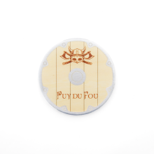 Magnet rond effet bois beige avec casque viking à cornes et haches croisées gravées en cuivre, logo Puy du Fou