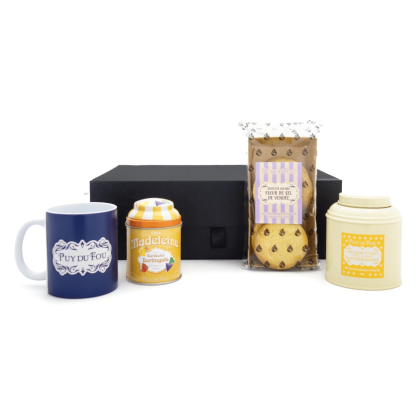Contenu du coffret cadeau gourmand sucré du Puy du Fou devant la boîte  avec mug 1900 bleu, berlingots, galettes fleur de sel et boîte de thé.