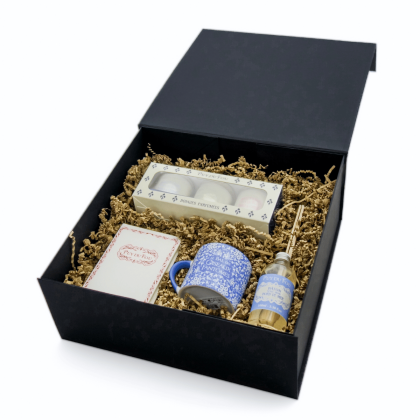 Coffret Maison & Senteurs ouvert en perspective : trois bougies parfumées, carnet A6, mini mug bleu et diffuseur parfum bord de mer rangés dans la boîte.