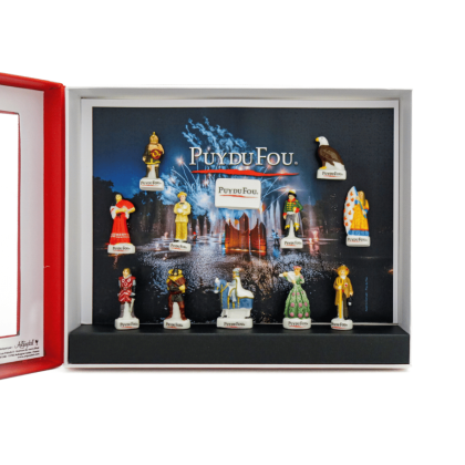 Coffret Puy du Fou ouvert, vue rapprochée sur l’intérieur : 12 fèves en porcelaine fixées dans la boîte, avec une fève “Puy du Fou” au centre.