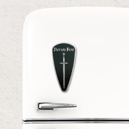 Magnet bouclier Exkalibur noir fixé sur réfrigérateur blanc vintage montrant son usage décoratif et pratique