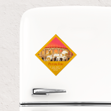 Magnet souvenir Puy du Fou Le Signe du Triomphe collé sur un réfrigérateur blanc, illustration d'un aurige sur char blanc dans une arène romaine