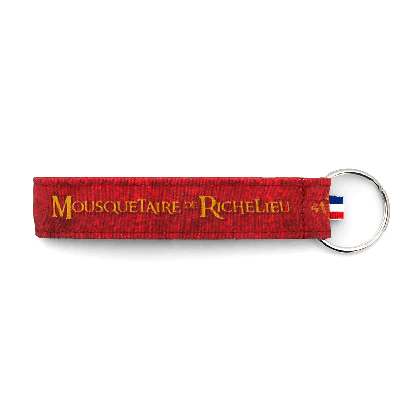 Porte-clés tissu Puy du Fou Mousquetaire de Richelieu – détail de l'inscription dorée sur fond rouge cardinal