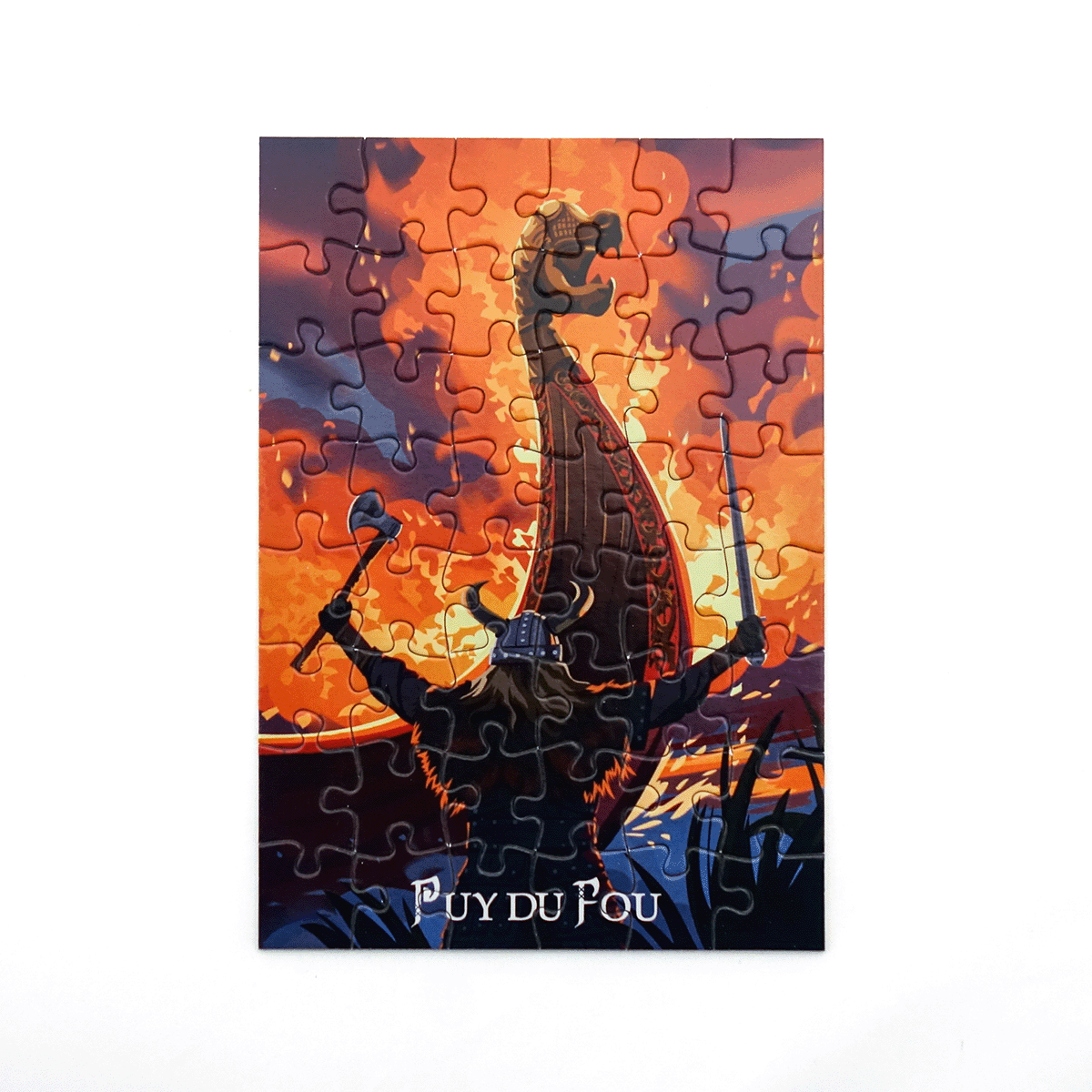 Puzzle assemblé Les Vikings montrant un drakkar noir avec guerrier brandissant une hache sur fond de ciel orange et violet flamboyant, logo Puy du Fou