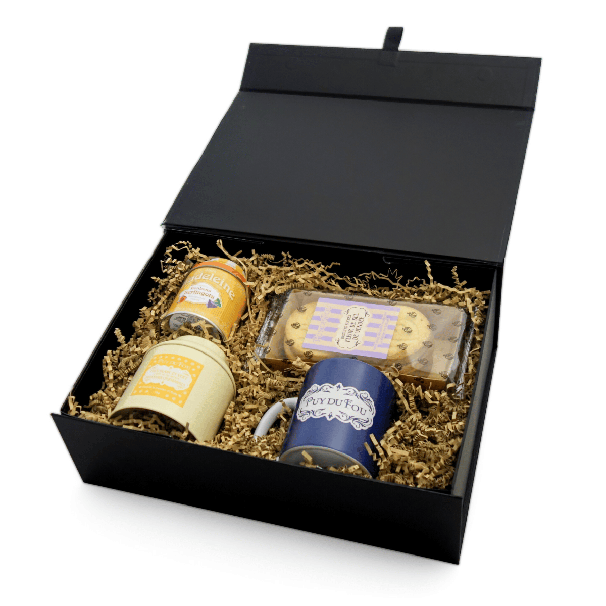 Coffret gourmand sucré ouvert contenant berlingots, galettes, thé blanc et vert et mug Puy du Fou rangés dans une boîte noire aimantée.