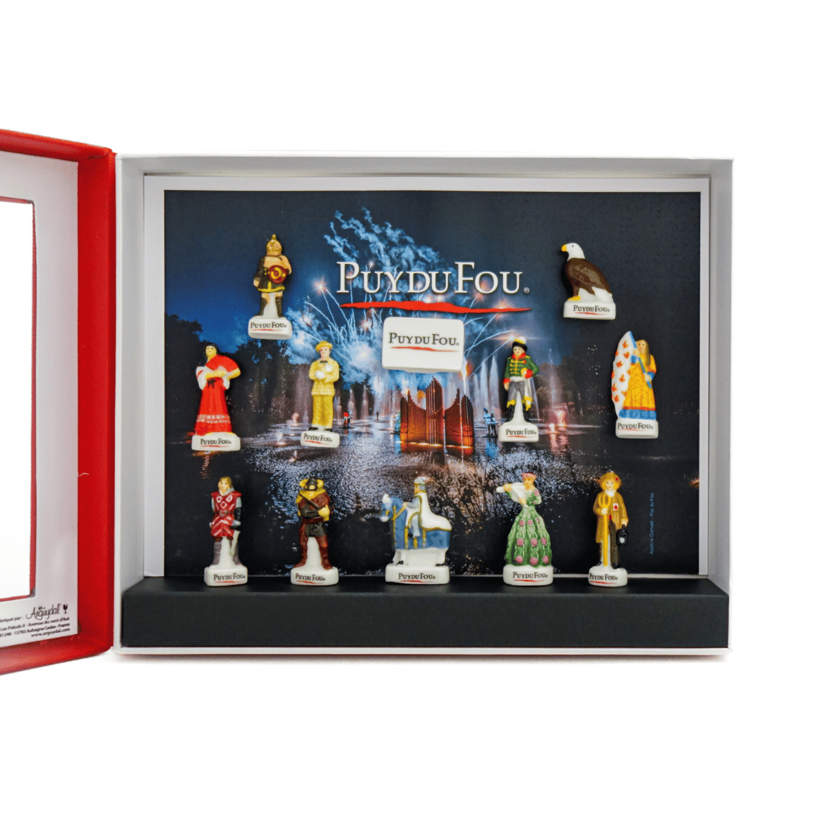 Coffret Puy du Fou ouvert, vue rapprochée sur l’intérieur : 12 fèves en porcelaine fixées dans la boîte, avec une fève “Puy du Fou” au centre.