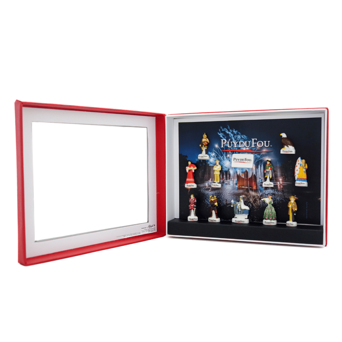 Coffret de 12 fèves Puy du Fou ouvert en deux volets : couvercle rouge à gauche, intérieur à droite avec les fèves en porcelaine disposées sur fond “Puy du Fou”.