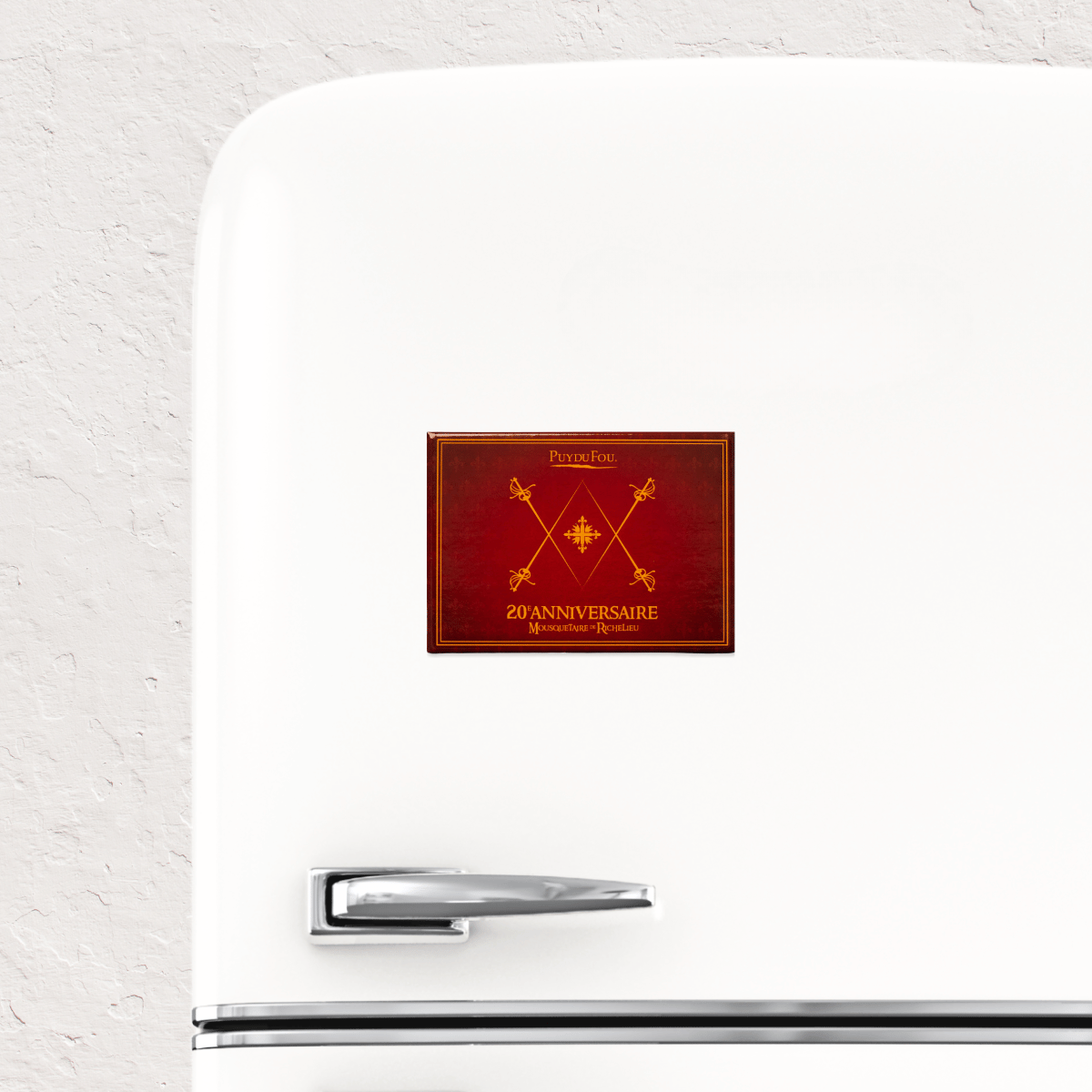 Magnet 20e anniversaire Mousquetaire de Richelieu Puy du Fou posé sur un réfrigérateur blanc, illustration de son utilisation