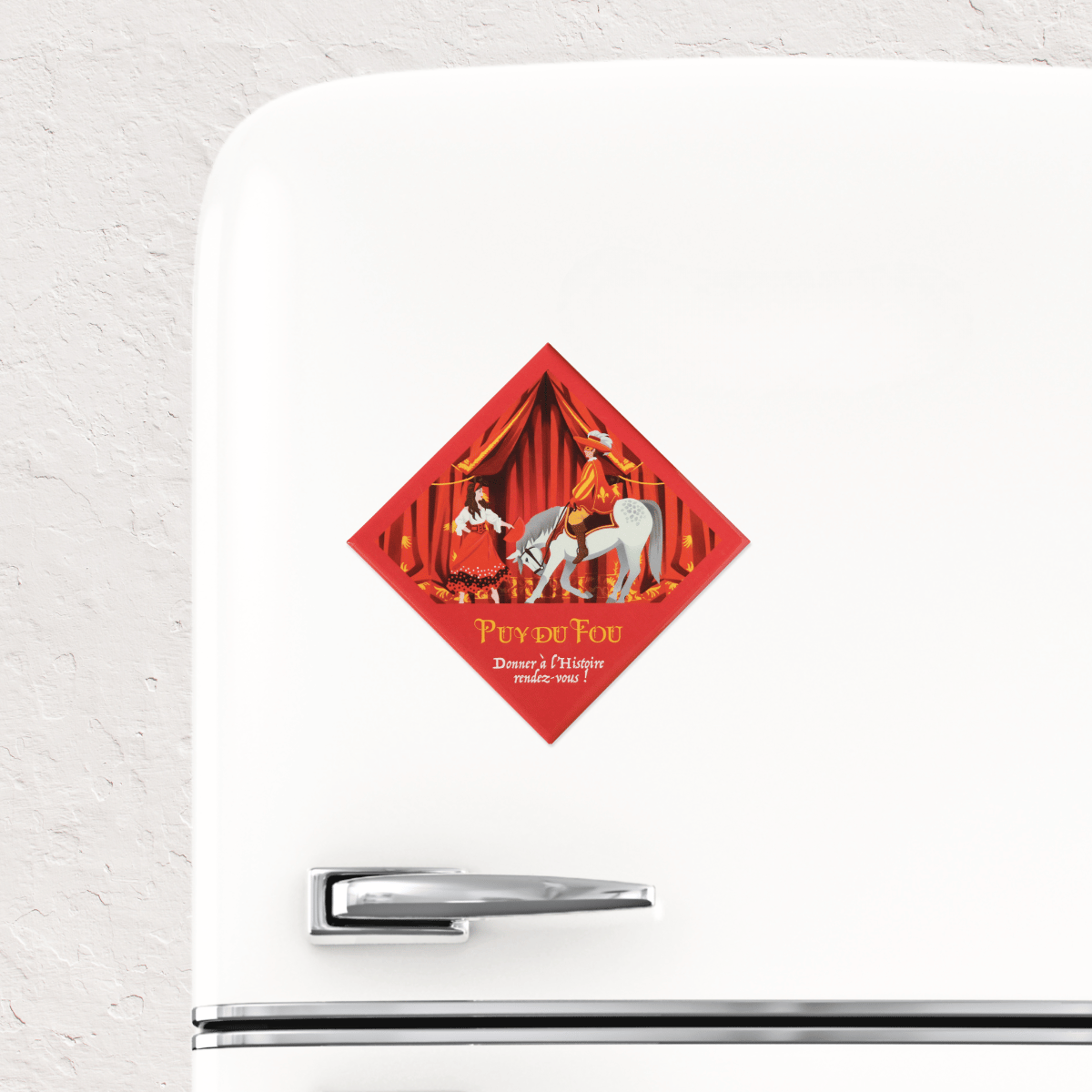 Magnet souvenir Puy du Fou Les Mousquetaires de Richelieu collé sur un réfrigérateur blanc, illustration d'un mousquetaire à cheval et de Serafina en robe rouge