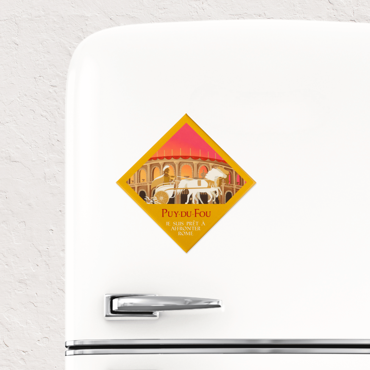Magnet souvenir Puy du Fou Le Signe du Triomphe collé sur un réfrigérateur blanc, illustration d'un aurige sur char blanc dans une arène romaine