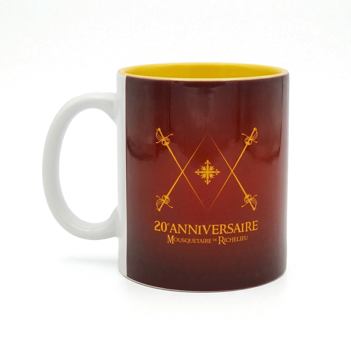 Mug édition spéciale 20 ans Mousquetaire de Richelieu Puy du Fou, détail fleurets de mousquetaires croisés et inscription anniversaire en or sur céramique bordeaux